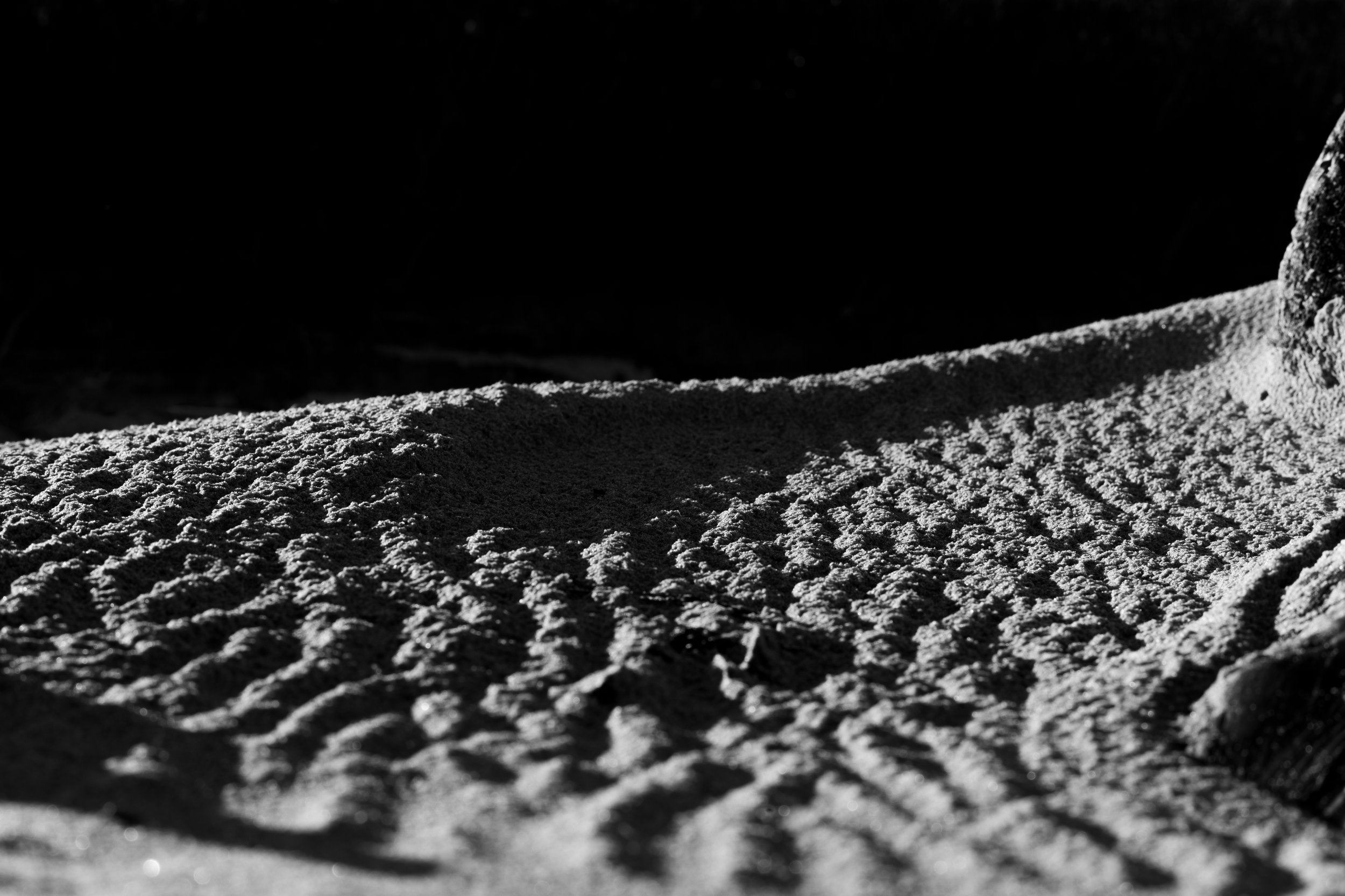 Wind-rippled sand rising to a rock edge